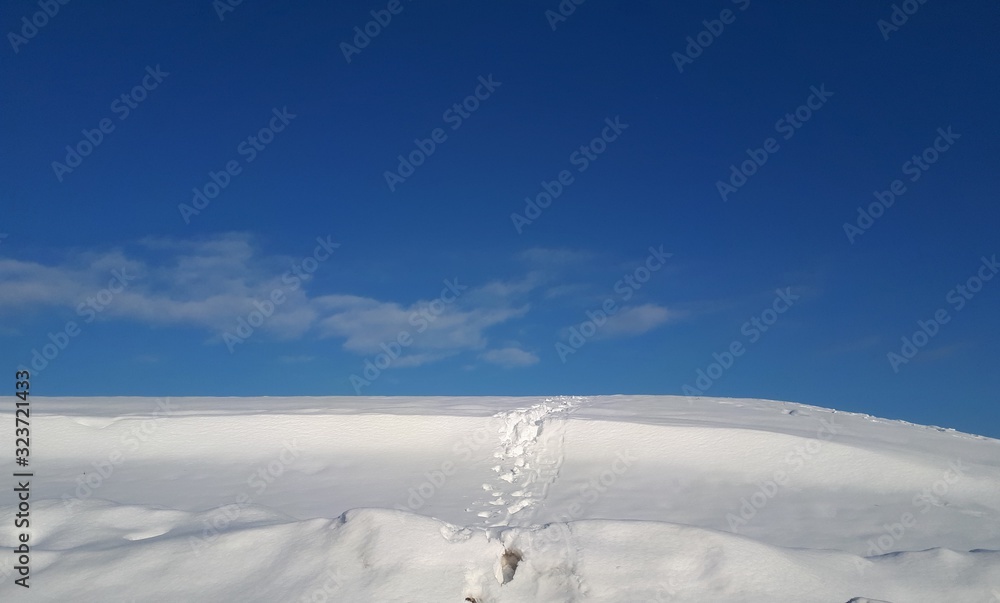 Footprints in snow over a hill