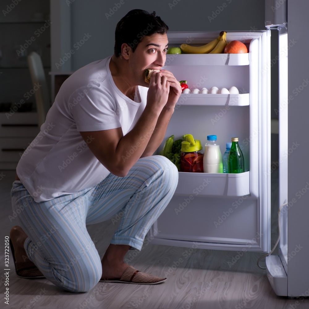 Man at the fridge eating at night Man at the fridge eating at night