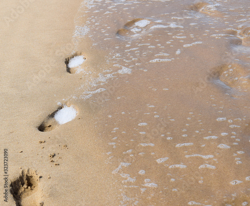 Footprints in the sand washed away by waves at beach