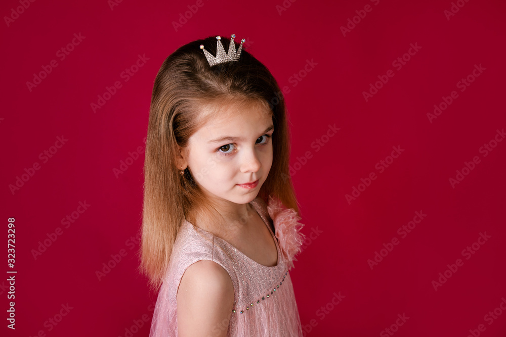 Beautiful little girl princess dancing in luxury pink and silver dress isolated on red background. Funny face, different emotions Beautiful little girl princess dancing in luxury pink and silver dress isolated on red background. Funny face, different emotions