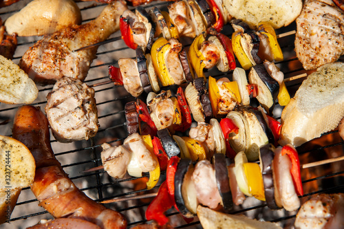 Closeup of snacks roasting over the fireplace. Meat and vegetable shashliks, rolls, and chicken.