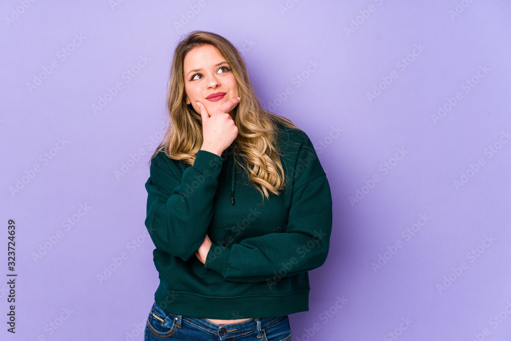 Young caucasian woman isolated on purple background thinking and looking up, being reflective, contemplating, having a fantasy. Young caucasian woman isolated on purple background thinking and looking up, being reflective, contemplating, having a fantasy.