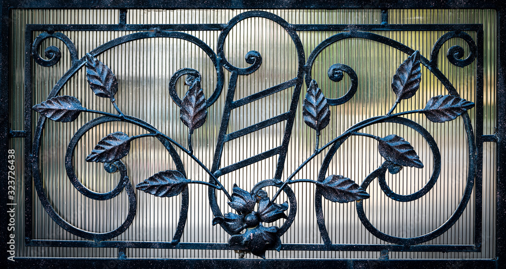 Details, structure and ornaments of forged iron gate. Decorative ornamen with roses, made from metal.