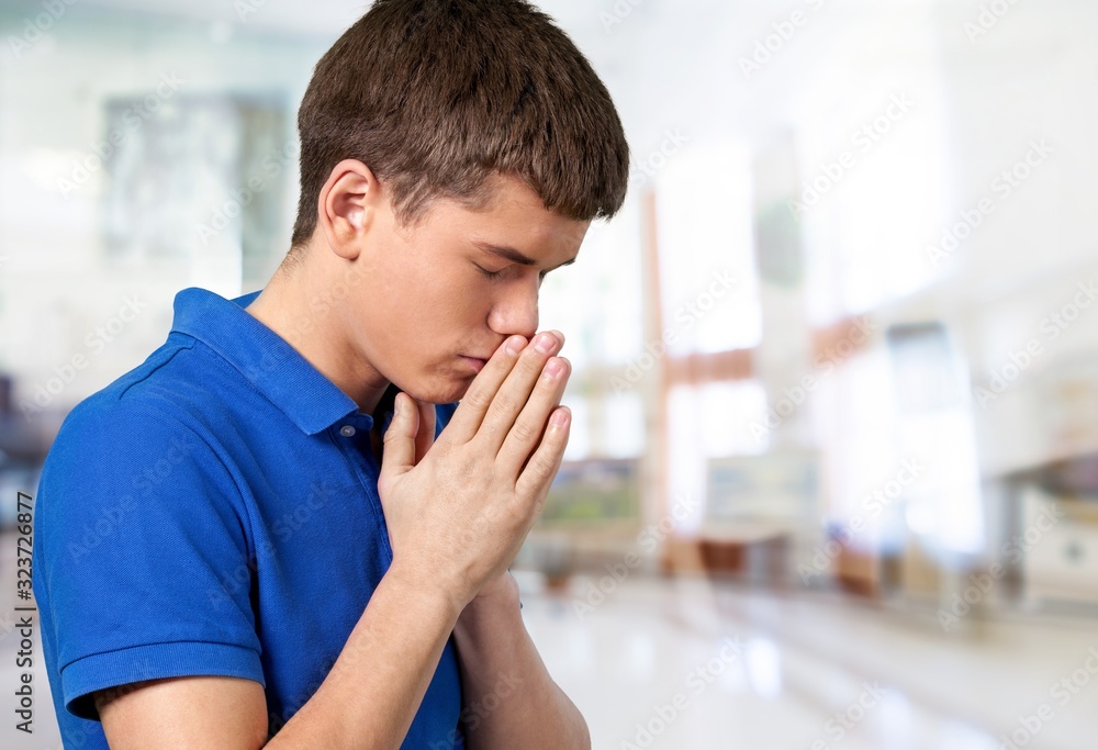 Beautiful young man prays on blur background Beautiful young man prays on blur background