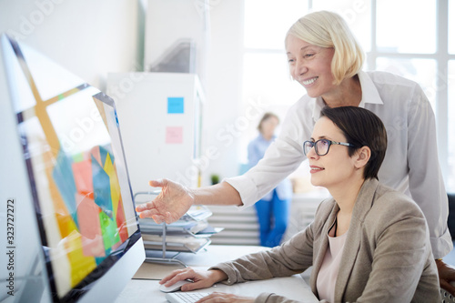 Konstfotografi Side view portrait of two businesswomen using computer in design agency