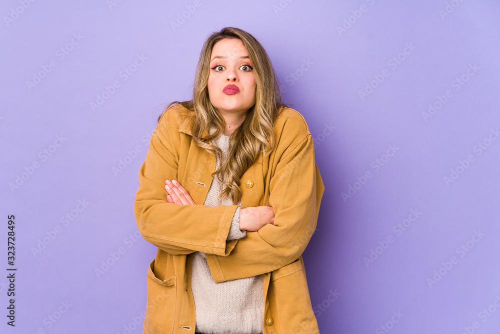 Young caucasian woman isolated on purple background shrugs shoulders and open eyes confused. Young caucasian woman isolated on purple background shrugs shoulders and open eyes confused.