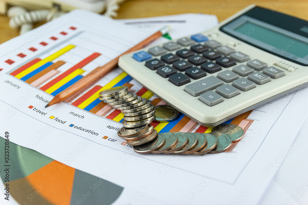 the stack of coin with business paper graphs and pencil with charts report, calculator, concept of calculating expenses, incomes and expenses. the stack of coin with business paper graphs and pencil with charts report, calculator, concept of calculating expenses, incomes and expenses.