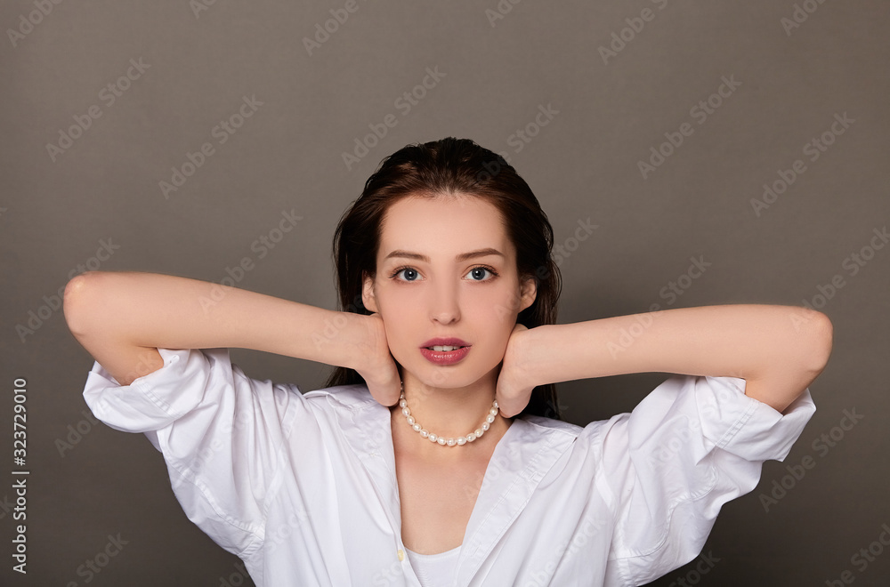 Beautiful young woman with wet hair puts on pearl beads. Beautiful young woman with wet hair puts on pearl beads.