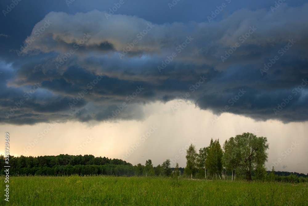 Rural landscape green field with dramatic sky. Grey dark sky before thunderstorm in summer. Rural landscape green field with dramatic sky. Grey dark sky before thunderstorm in summer.