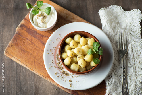 Delicious dish of round potato gnocchi accompanied by cheese sauce with the necessary accessories to taste them