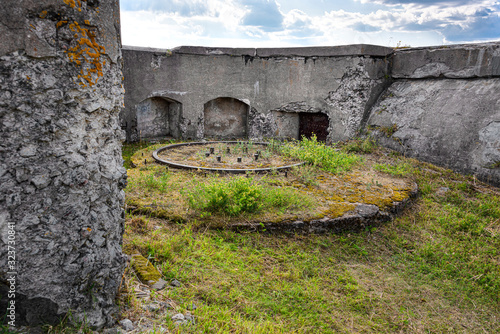 Finland, Sveaborg, Suomenlinna: Remainder of historic defencive work at the shoreline of the famous island near Finnish capital with gun pedestal, concrete wall, green grass, blue sky - war history. photo