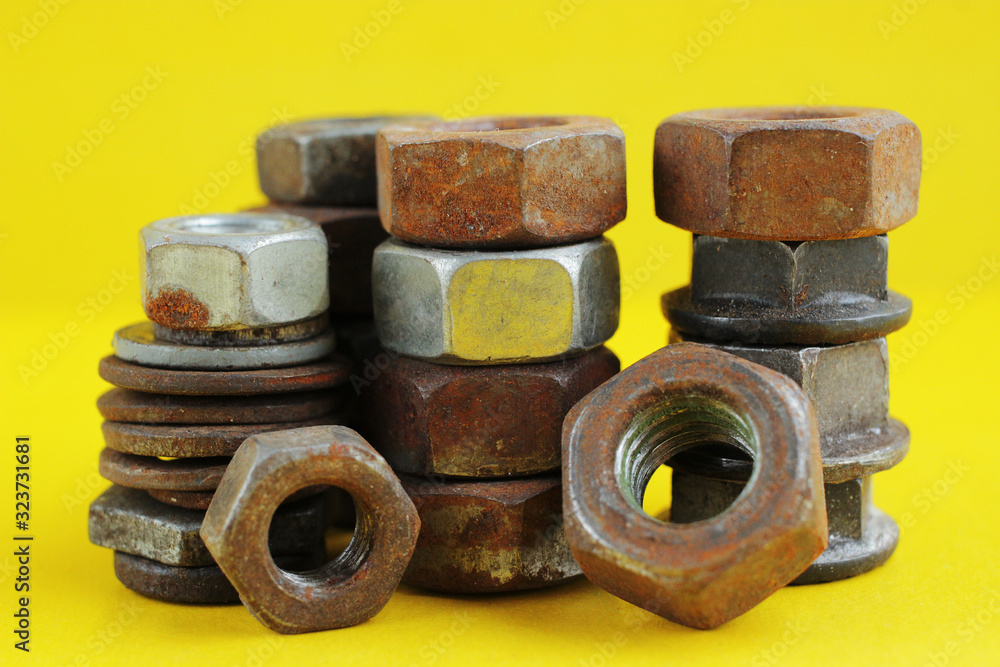 Piles of old rusty nuts different sizes, on a yellow background. Macro photography. Piles of old rusty nuts different sizes, on a yellow background. Macro photography.