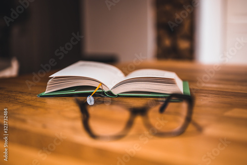 Open book and glasses on table. Book and glasses. © Peter