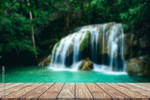 Beautiful waterfall in green forest  Front view wood table. 