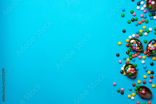 Easter blue background with multi-colored candy in a chocolate nest