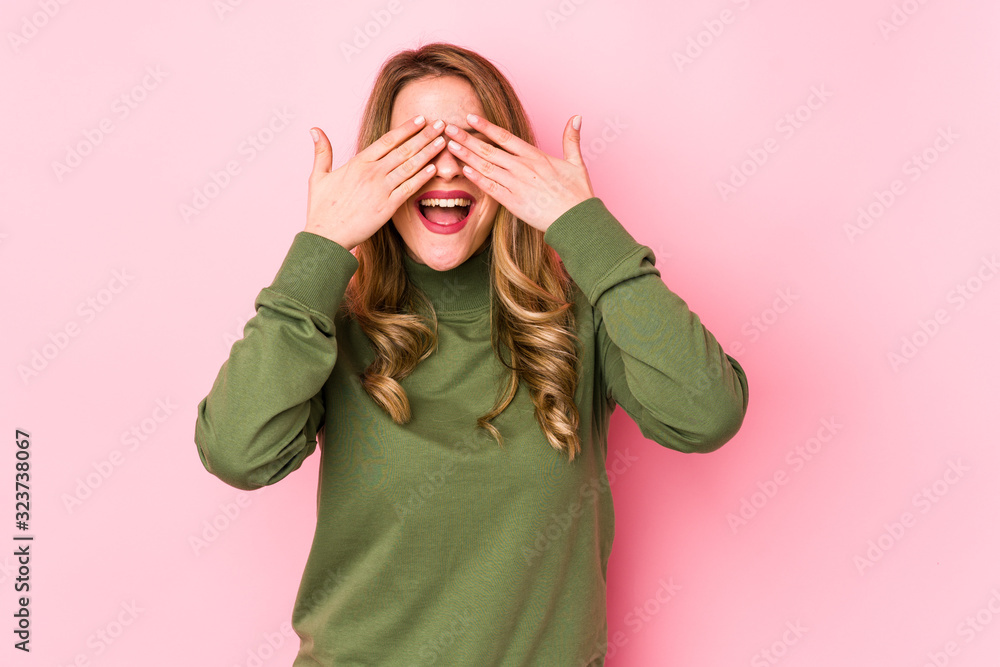 Young caucasian woman isolated on pink background covers eyes with hands, smiles broadly waiting for a surprise. Young caucasian woman isolated on pink background covers eyes with hands, smiles broadly waiting for a surprise.