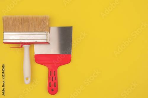 Big brush of the painter and spatula on a yellow background.