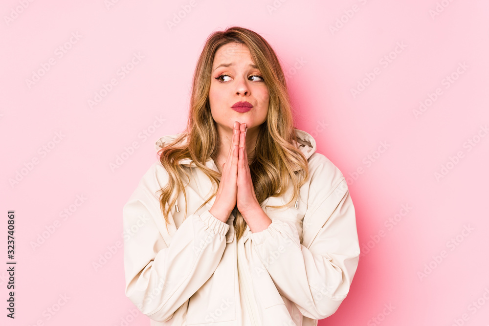 Young caucasian woman isolated on pink background praying, showing devotion, religious person looking for divine inspiration. Young caucasian woman isolated on pink background praying, showing devotion, religious person looking for divine inspiration.