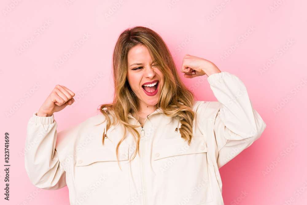 Young caucasian woman isolated on pink background raising fist after a victory, winner concept. Young caucasian woman isolated on pink background raising fist after a victory, winner concept.