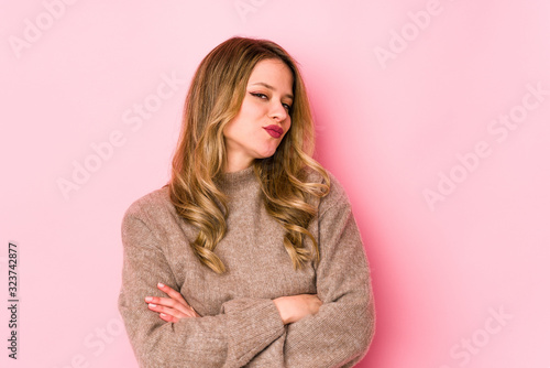 Young caucasian woman isolated on pink background suspicious, uncertain, examining you. © Asier