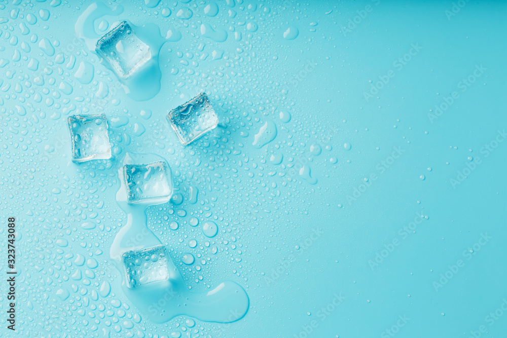 Ice cubes with water drops scattered on a blue background, top view. Ice cubes with water drops scattered on a blue background, top view.