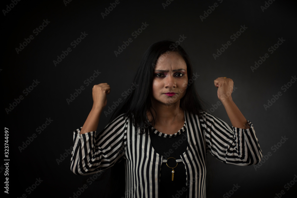 Fashion portrait of an young and attractive Indian Bengali brunette girl with striped western semi formal/casual dress in front of a black studio background. Indian fashion portrait and lifestyle. Fashion portrait of an young and attractive Indian Bengali brunette girl with striped western semi formal/casual dress in front of a black studio background. Indian fashion portrait and lifestyle.