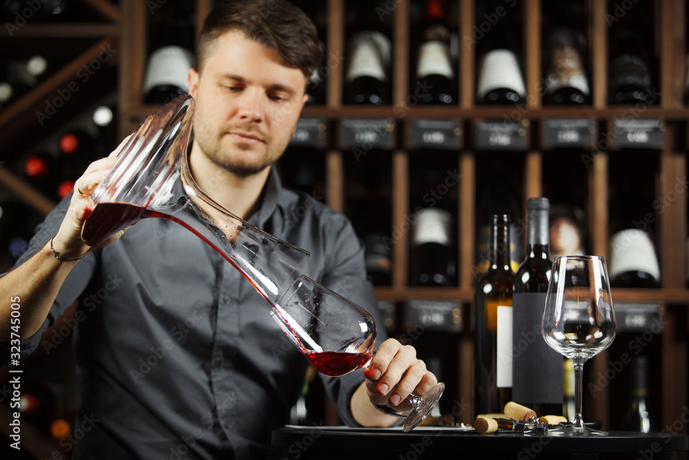 Sommelier pours red wine from decanter to the glass