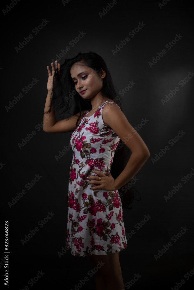 Fashion portrait of an young and attractive Indian Bengali brunette girl with floral western dress in front of a black studio background. Indian fashion portrait and lifestyle. Fashion portrait of an young and attractive Indian Bengali brunette girl with floral western dress in front of a black studio background. Indian fashion portrait and lifestyle.