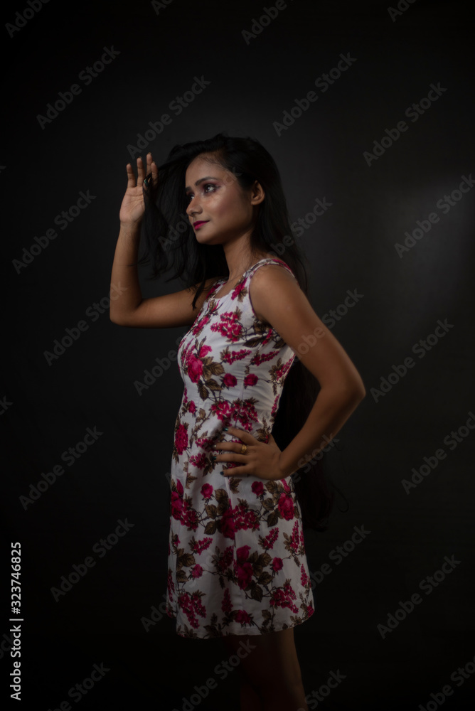 Fashion portrait of an young and attractive Indian Bengali brunette girl with floral western dress in front of a black studio background. Indian fashion portrait and lifestyle. Fashion portrait of an young and attractive Indian Bengali brunette girl with floral western dress in front of a black studio background. Indian fashion portrait and lifestyle.