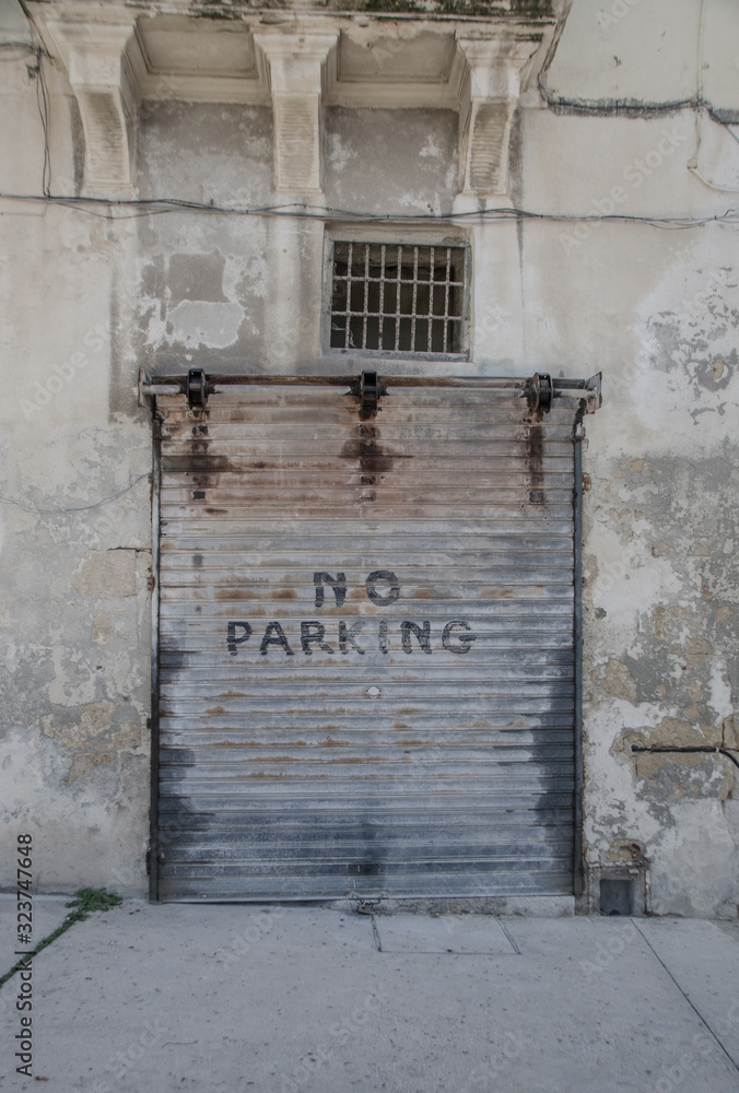 Street scene in Valetta with roller shutter on which the 'no parking' warning has been painted.