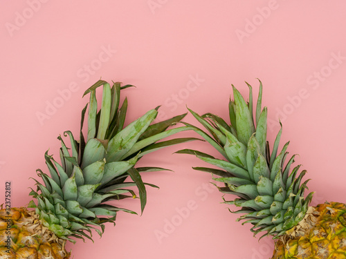 Top view of isolated pineapples lying on a pink background with space for text at the top of the image. Concept of tropical fruit.