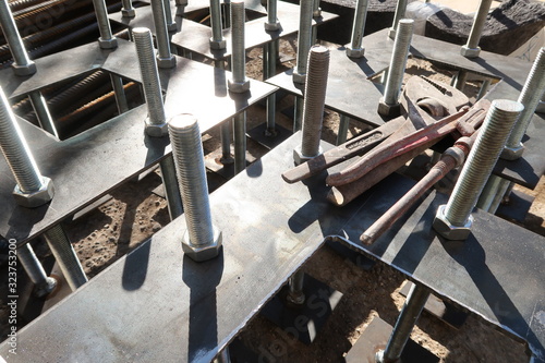 Construction site for a building with a steel structure. Plates with anchor bolts for mounting steel columns on a reinforced concrete foundation.