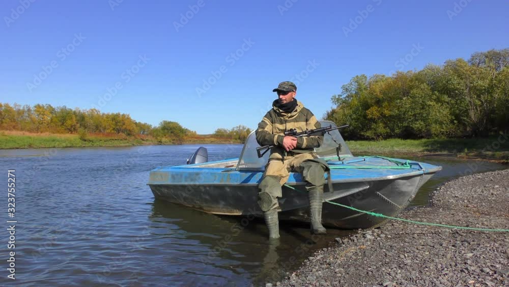 River fishing for salmon. A hunter with a carbine guards fishermen on the river from bears. Kamchatka Peninsula, Russia.