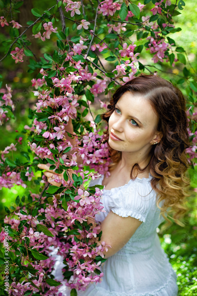 pensive girl near a blooming pink branch pensive girl near a blooming pink branch