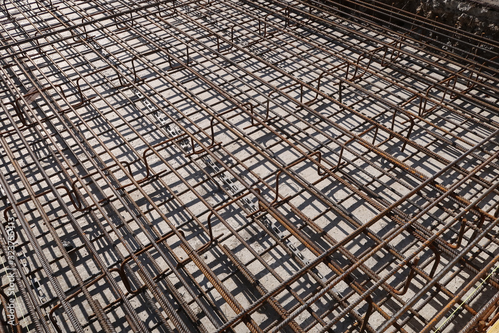 Dense texture of steel rods of a reinforced concrete foundation. Construction site.