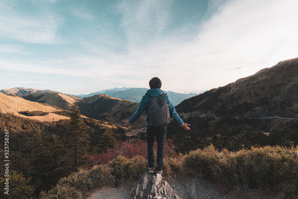 Young traveler standing and looking at beautiful landscape on top of mountain