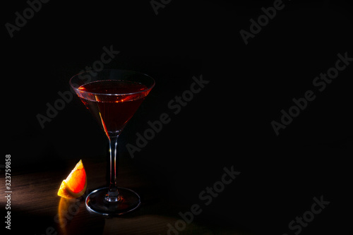 bright cocktail with red orange in a ray of light on a dark background