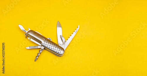 Close up photo of swiss army knife on yellow background with copy space photo