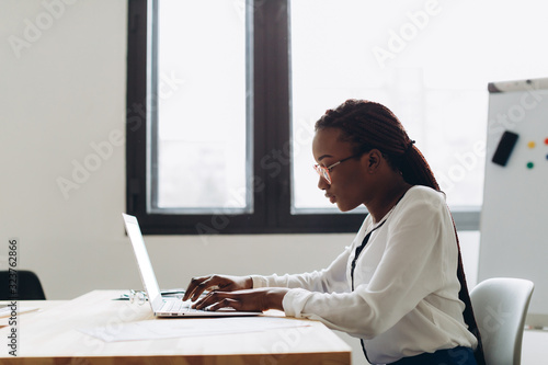 Pretty african american business woman working on laptop in office