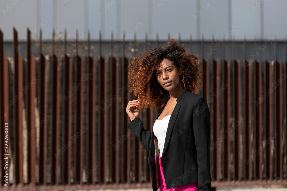 Fototapeta premium Portrait of a beautiful afro american woman standing in the street in a sunny day