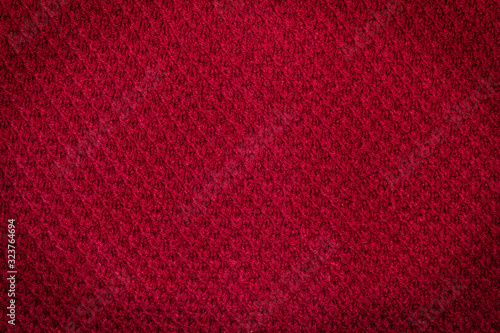 Background. Texture. Woolen knitted red fabric with darkened corners.