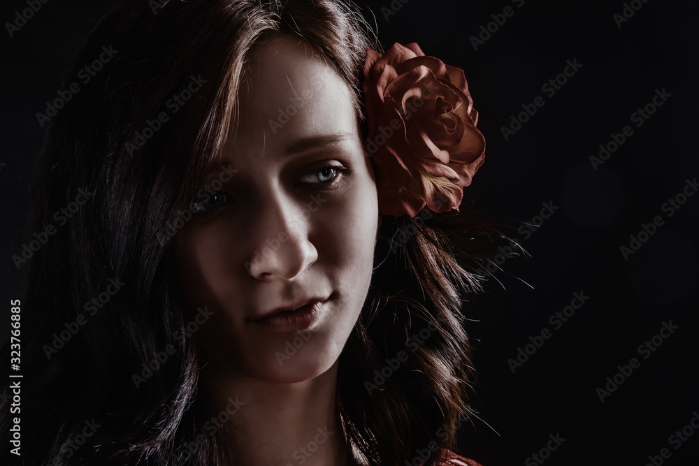 Mysterious portrait of a girl with a flower in her hair in a low key Mysterious portrait of a girl with a flower in her hair in a low key