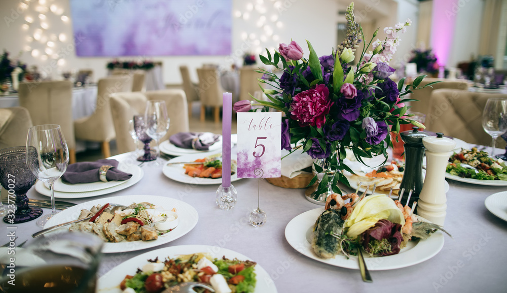 Ideas for wedding. Festive table setting with food on plate and purple flowers Ideas for wedding. Festive table setting with food on plate and purple flowers
