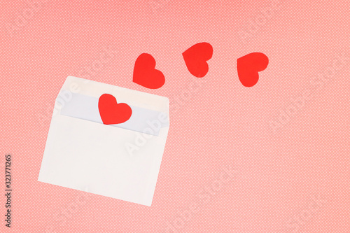 Red heart for Valentine's day and white envelope on pink background 