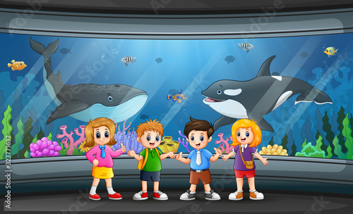 Funny school children looking at fish in aquarium