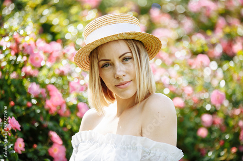 girl in a white dress with a hat in the garden with pink roses