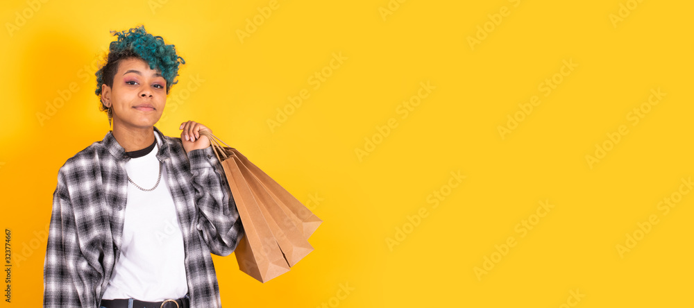 young brunette girl with shopping bags isolated on yellow background young brunette girl with shopping bags isolated on yellow background
