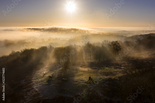 Silhouette of a man and child standing in the British countryside mist at sunrise