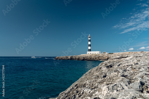 Majestic Artrutx lighthouse on the beautiful rocky coastline of western Menorca island, Spain