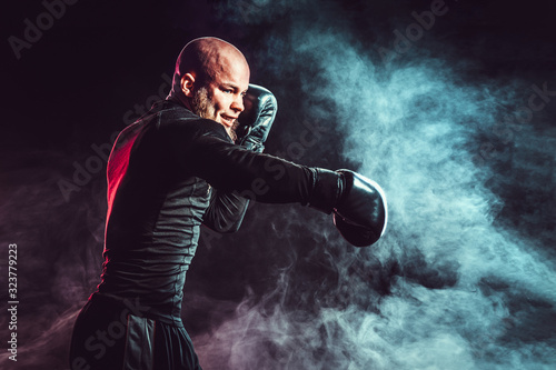 Fototapeta Naklejka Na Ścianę i Meble -  Sportsman boxer fighting on black background with smoke. Boxing sport concept.